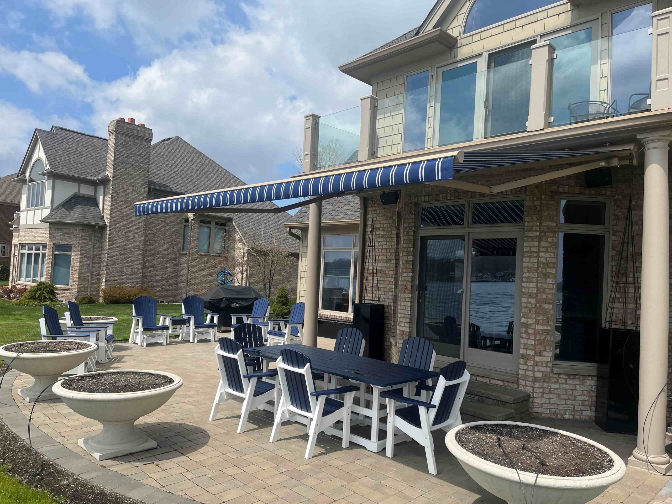 Blue awning with white stripes over patio table and chairs