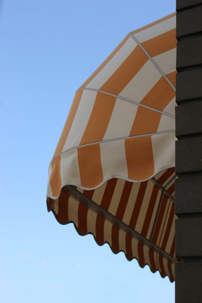 Yellow and white striped window awning fully extended over residential window