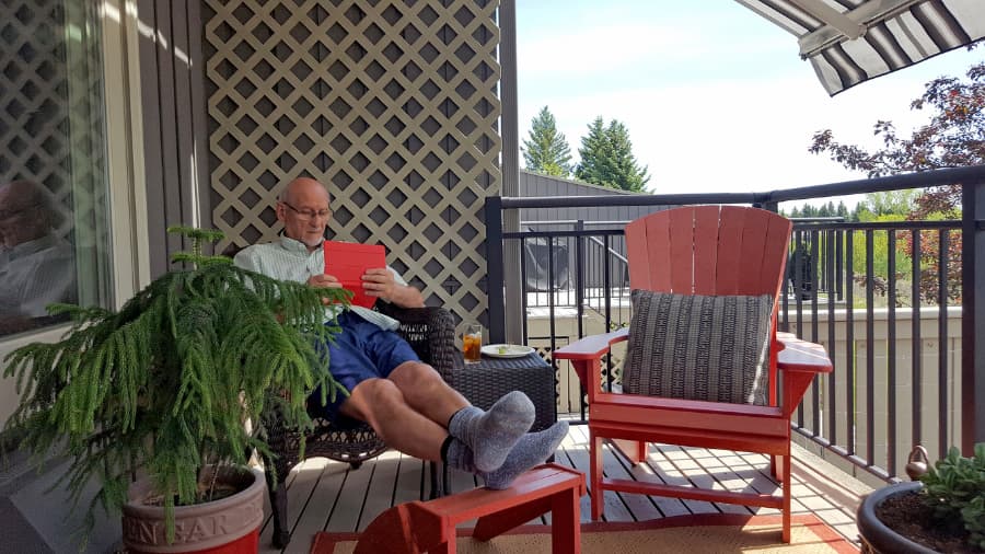 Person in chair reads on deck in shade of retractable awning